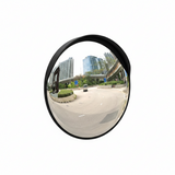 Convex mirror reflecting an urban street scene with buildings and a car.