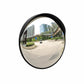 Convex mirror showing a wide view of an urban street with buildings and a car.