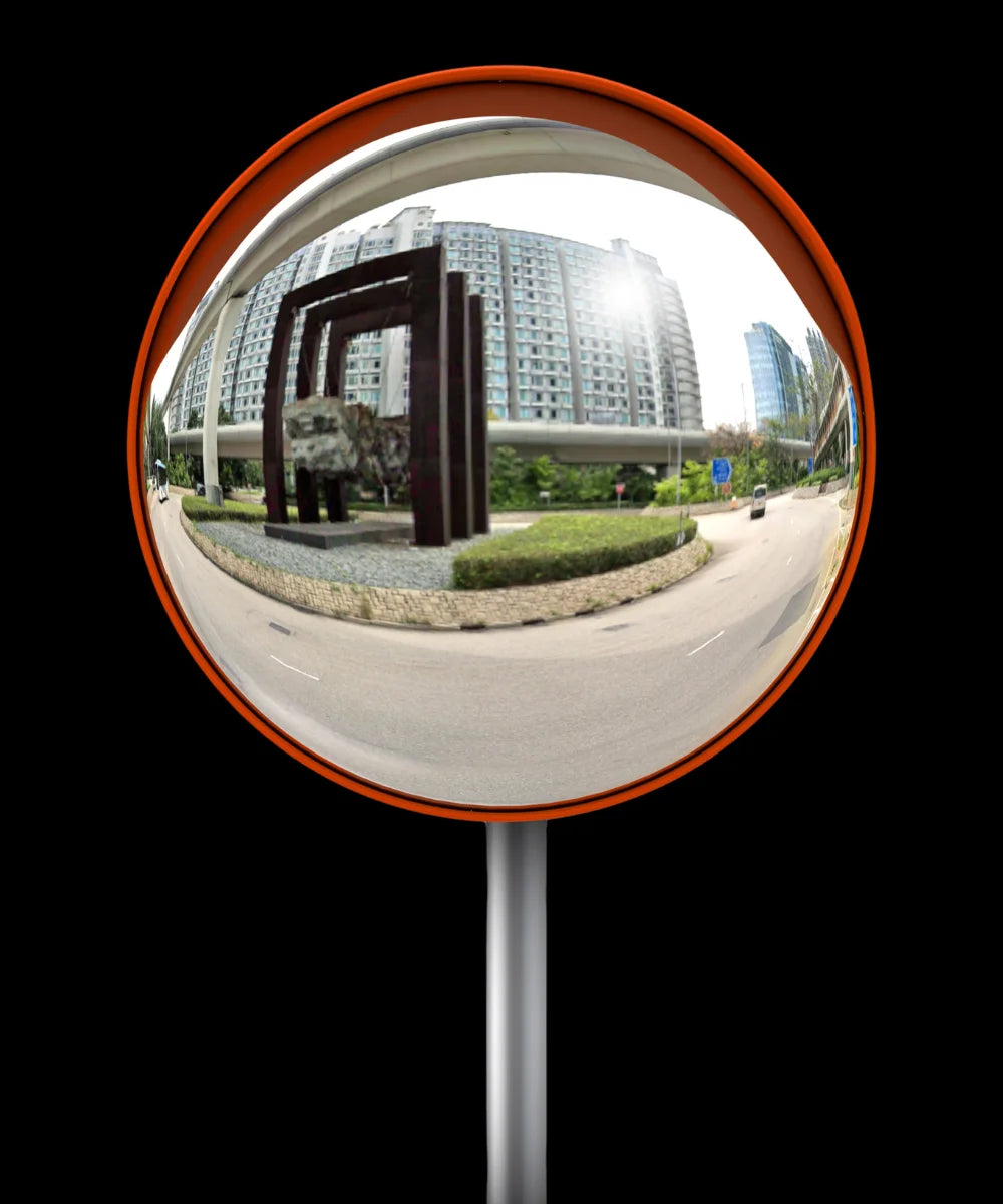 Convex traffic mirror reflecting a cityscape with buildings and road.