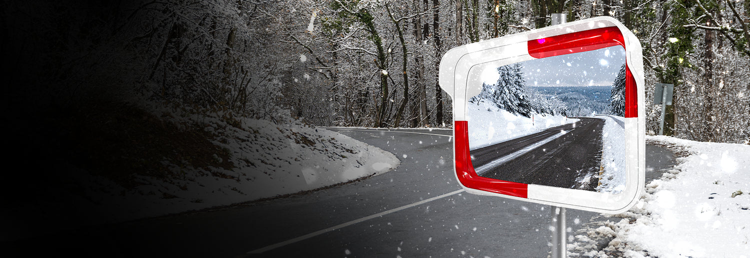 Car mirror reflecting a snowy road with trees on either side